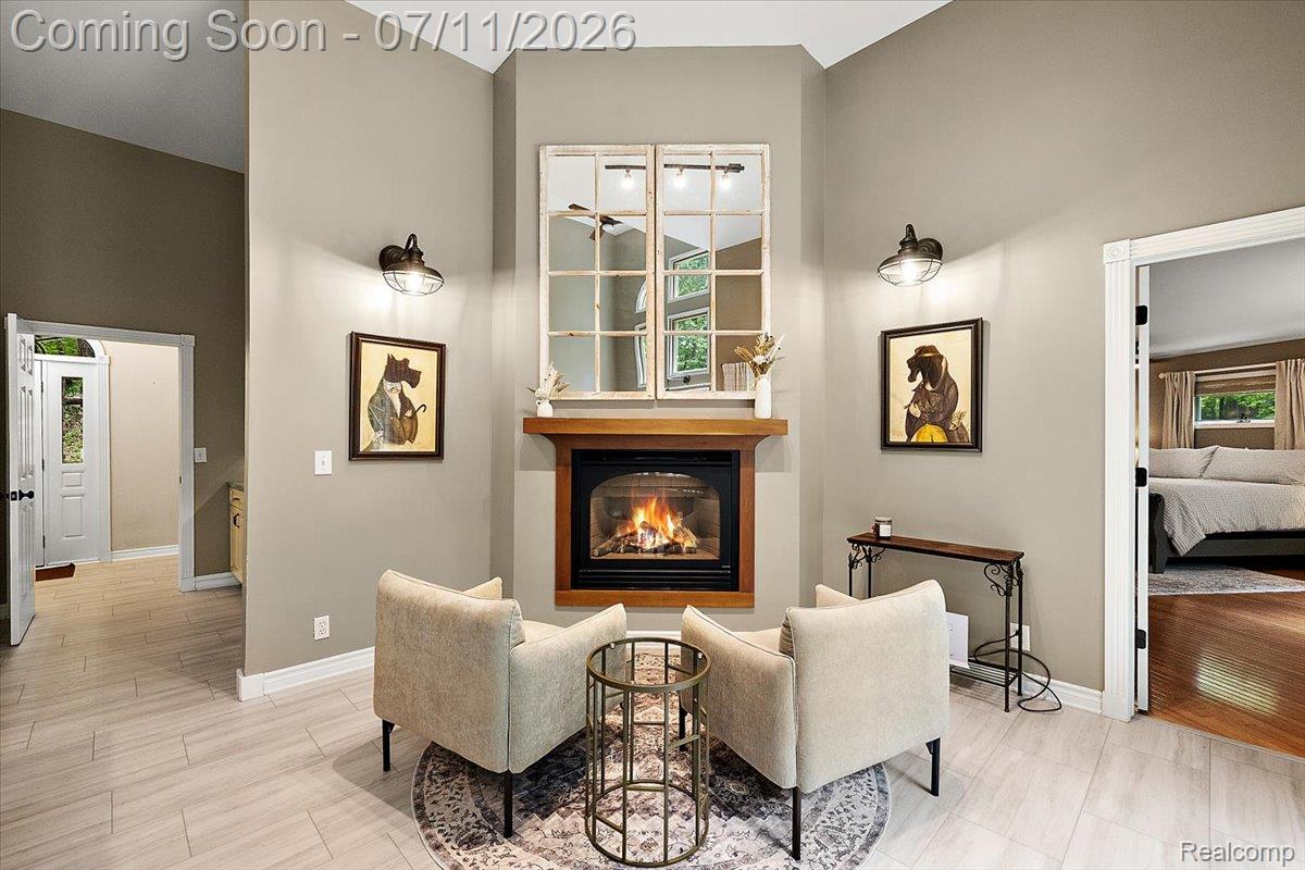 4219 Gardner Road Metamora, MI 48455 - Photo 20 of 87 Vaulted ceiling interior featuring a built-in fireplace with a wood mantle, light wood-finish flooring, wall-mounted sconces, and a window-pane style mirror