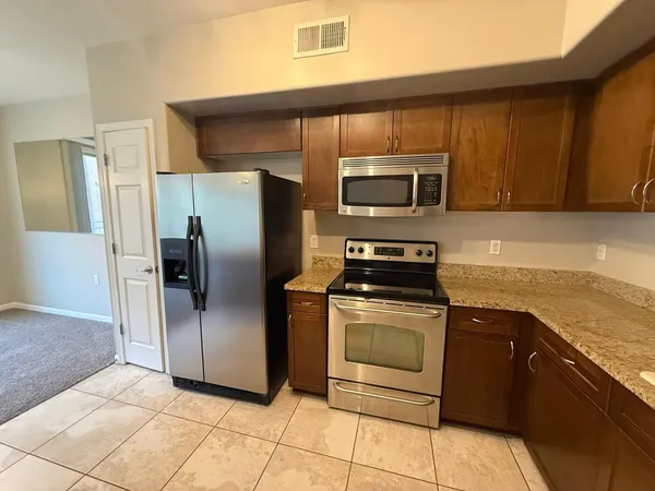 a kitchen with granite countertop a refrigerator and a stove top oven