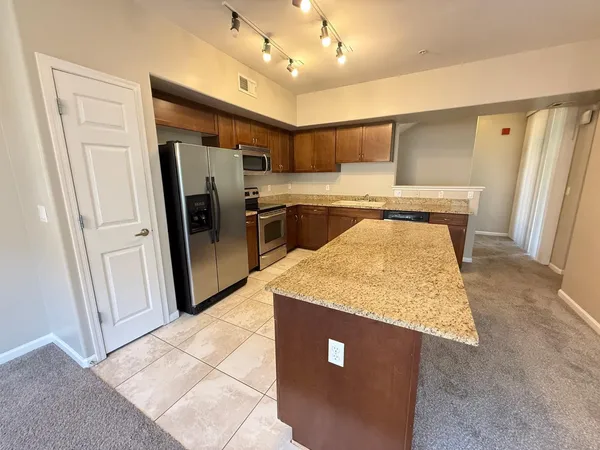 a kitchen with stainless steel appliances granite countertop a refrigerator a sink dishwasher and a stove with wooden floor