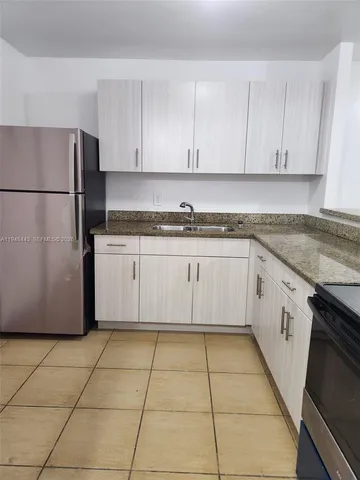 a kitchen with granite countertop a sink a stove a refrigerator and cabinets