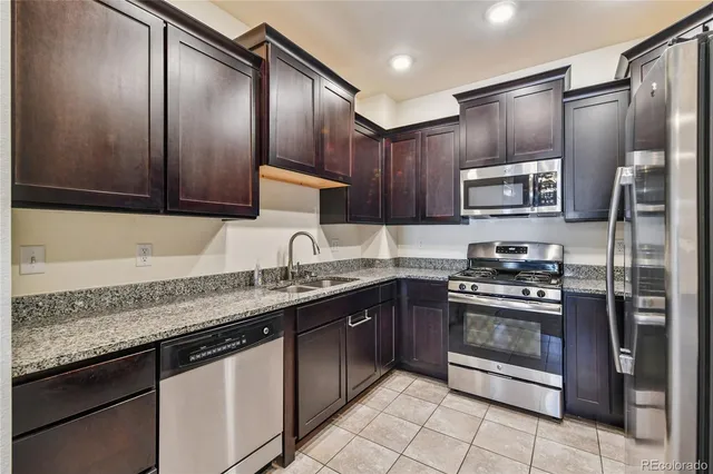 a kitchen with stainless steel appliances granite countertop wooden cabinets a sink and a stove
