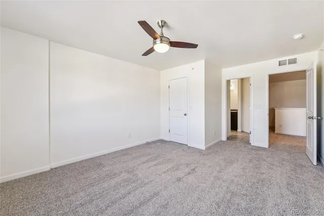 an empty room with closet and a ceiling fan
