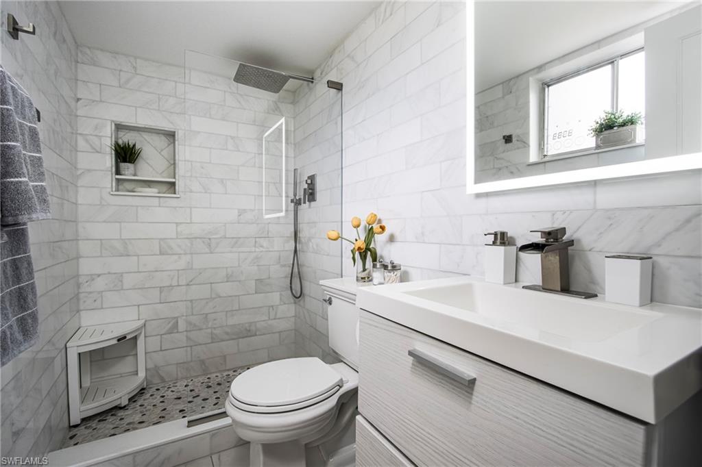 766 Central Avenue, Unit 112 Naples, FL 34102 - Photo 13 of 18 a bathroom with a sink a toilet and a mirror