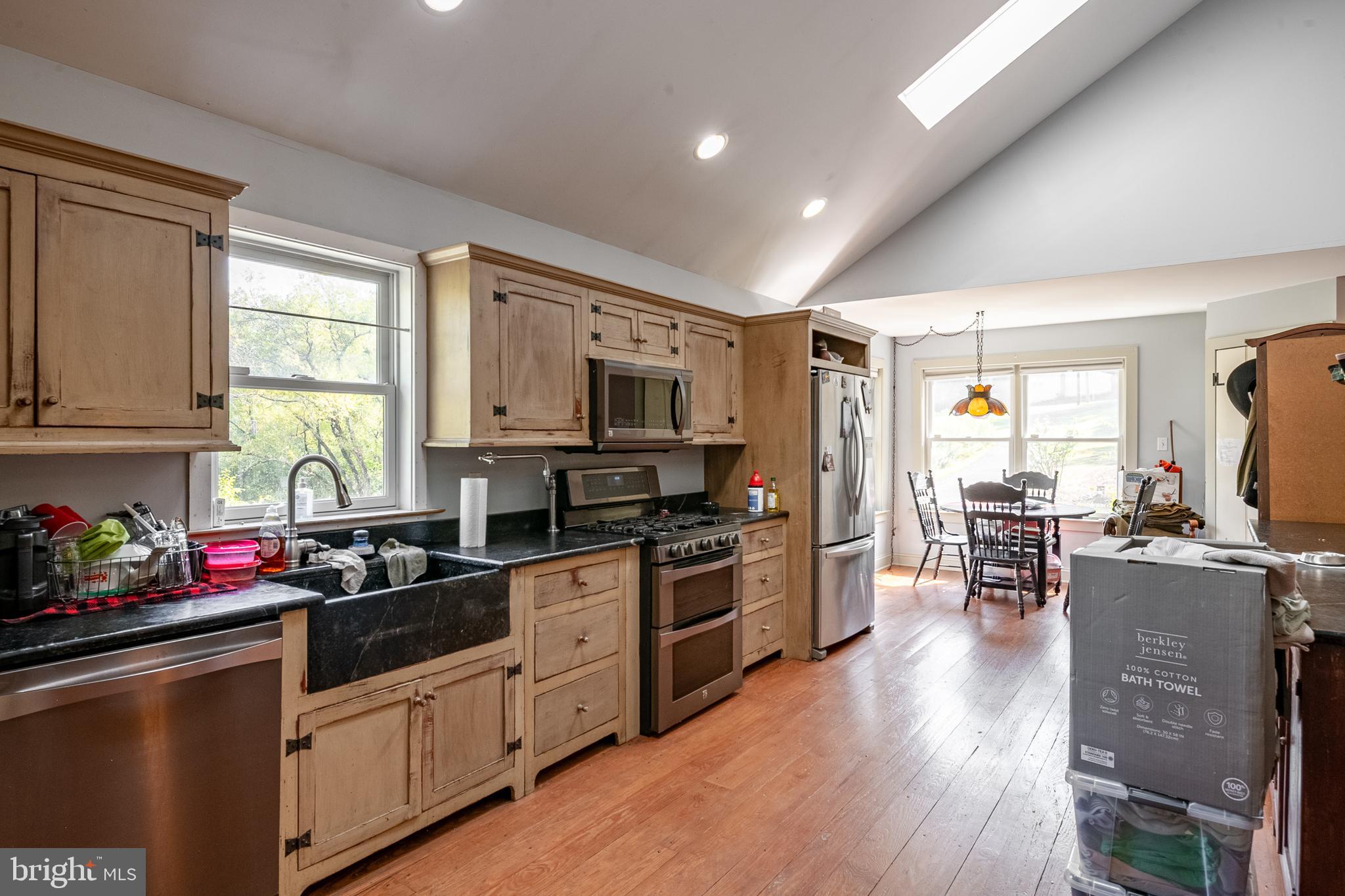 700 Fabers Road Reading, PA 19606 - Photo 14 of 33 a kitchen with stainless steel appliances granite countertop wooden cabinets a refrigerator a stove top oven a sink dishwasher and a dining table with wooden floor