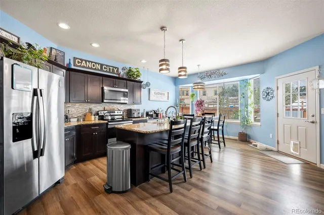 a kitchen with stainless steel appliances granite countertop wooden floors a stove and a refrigerator