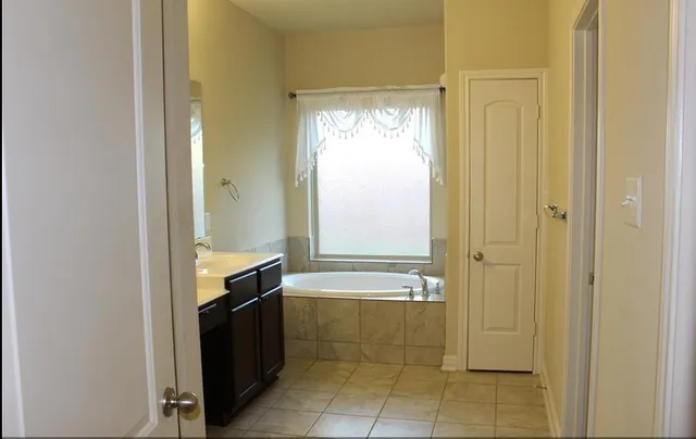 a bathroom with a granite countertop sink a mirror and a bathtub