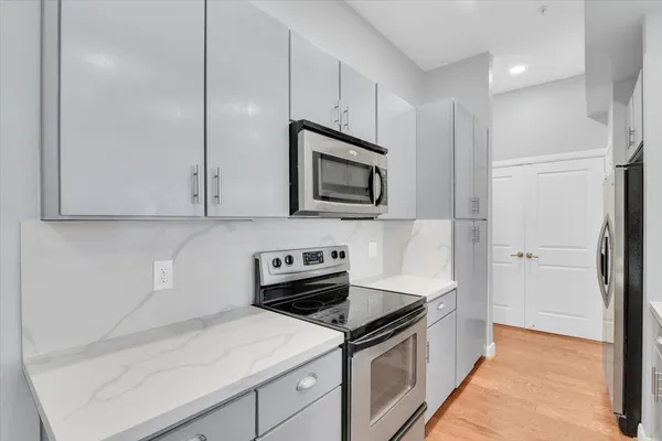 a large white kitchen with stainless steel appliances granite countertop a sink and cabinets