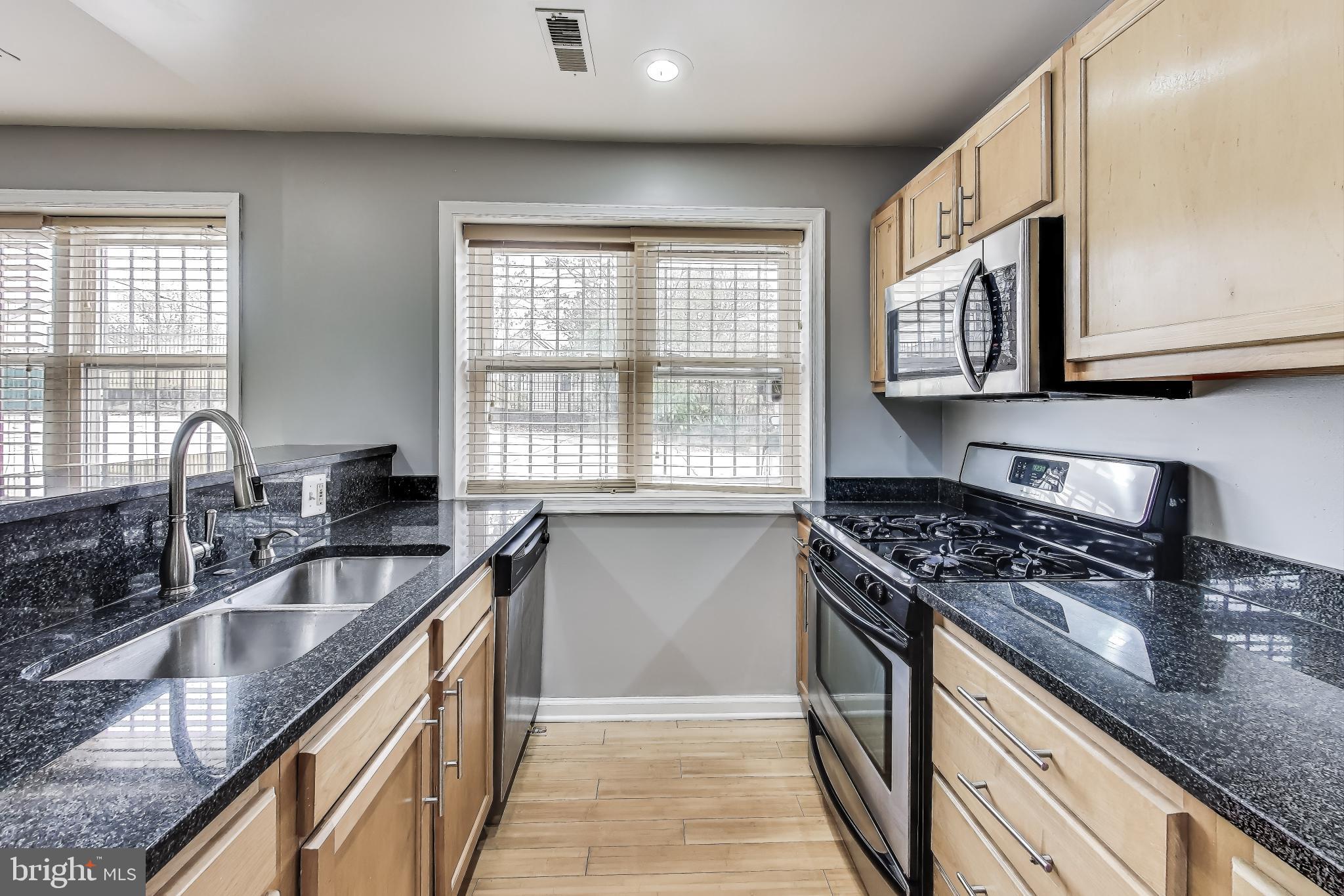 a kitchen with granite countertop a sink stove top oven and cabinets