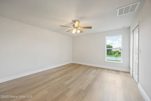 an empty room with wooden floor and a ceiling fan