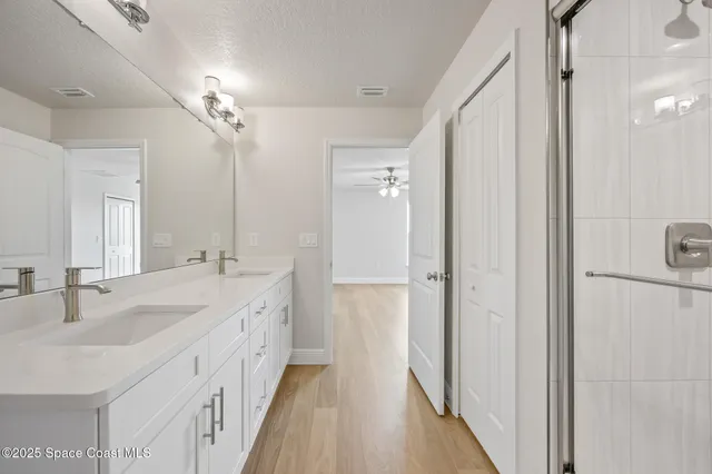 a spacious bathroom with a double vanity sink a mirror and shower