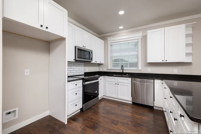 a kitchen with granite countertop white cabinets sink and stainless steel appliances