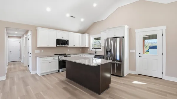 a kitchen with stainless steel appliances granite countertop a stove a sink dishwasher and a refrigerator with wooden floor