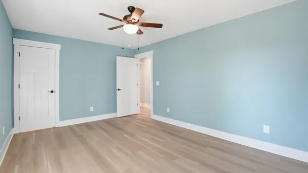 an empty room with windows and fan