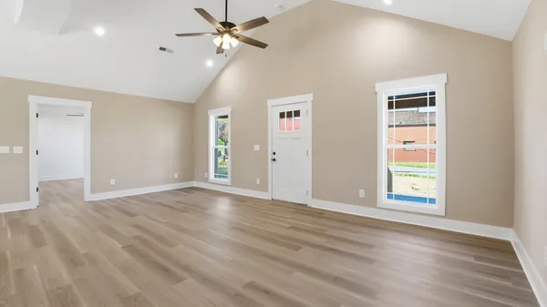 a view of an empty room with a window and wooden floor