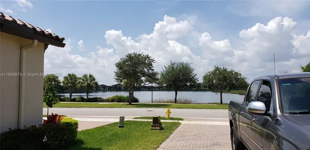 a view of swimming pool with seating space and trees in the background