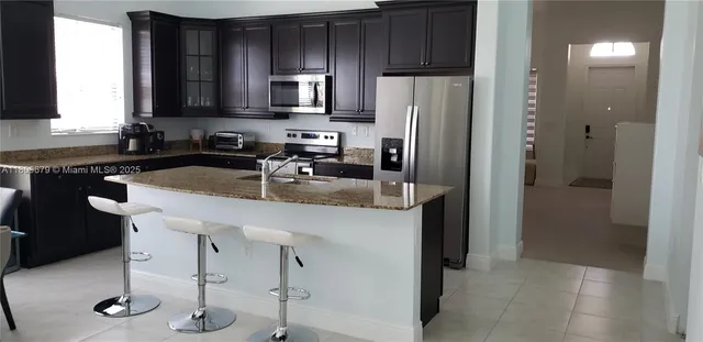 a kitchen with stainless steel appliances granite countertop a refrigerator a stove a sink and a counter space