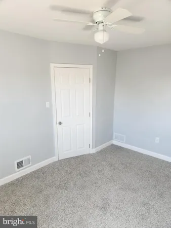 an empty room with a chandelier fan and closet