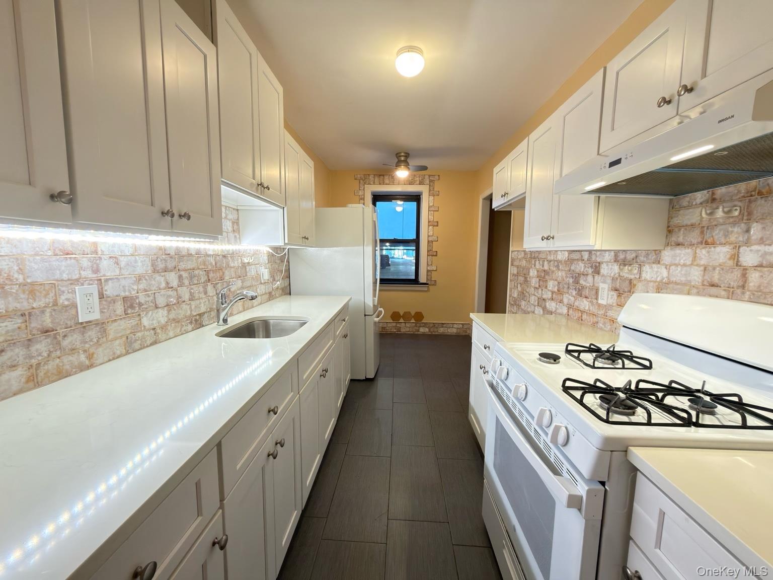 42 Barker Avenue, Unit 2B White Plains, NY 10601 - Photo 2 of 13 Kitchen featuring white appliances, white cabinets, under cabinet range hood, decorative backsplash, and a ceiling fan