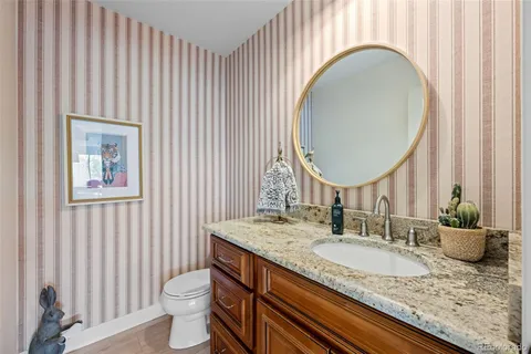a bathroom with a granite countertop toilet a sink and a mirror