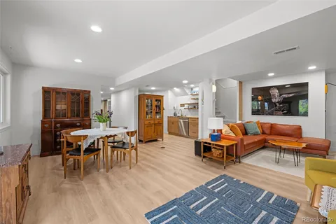 a living room with furniture a wooden floor and a view of kitchen