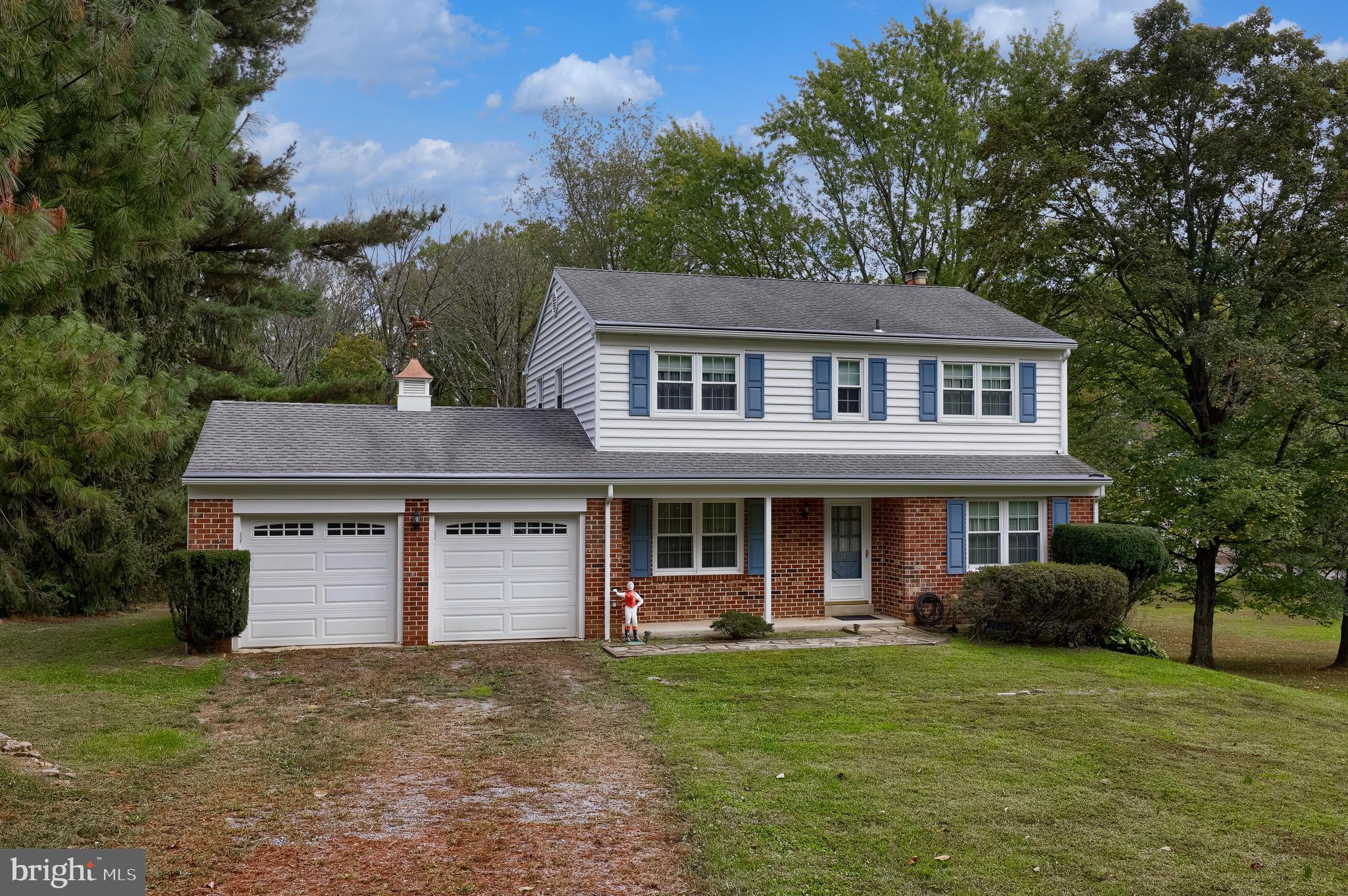 a front view of a house with a garden and trees