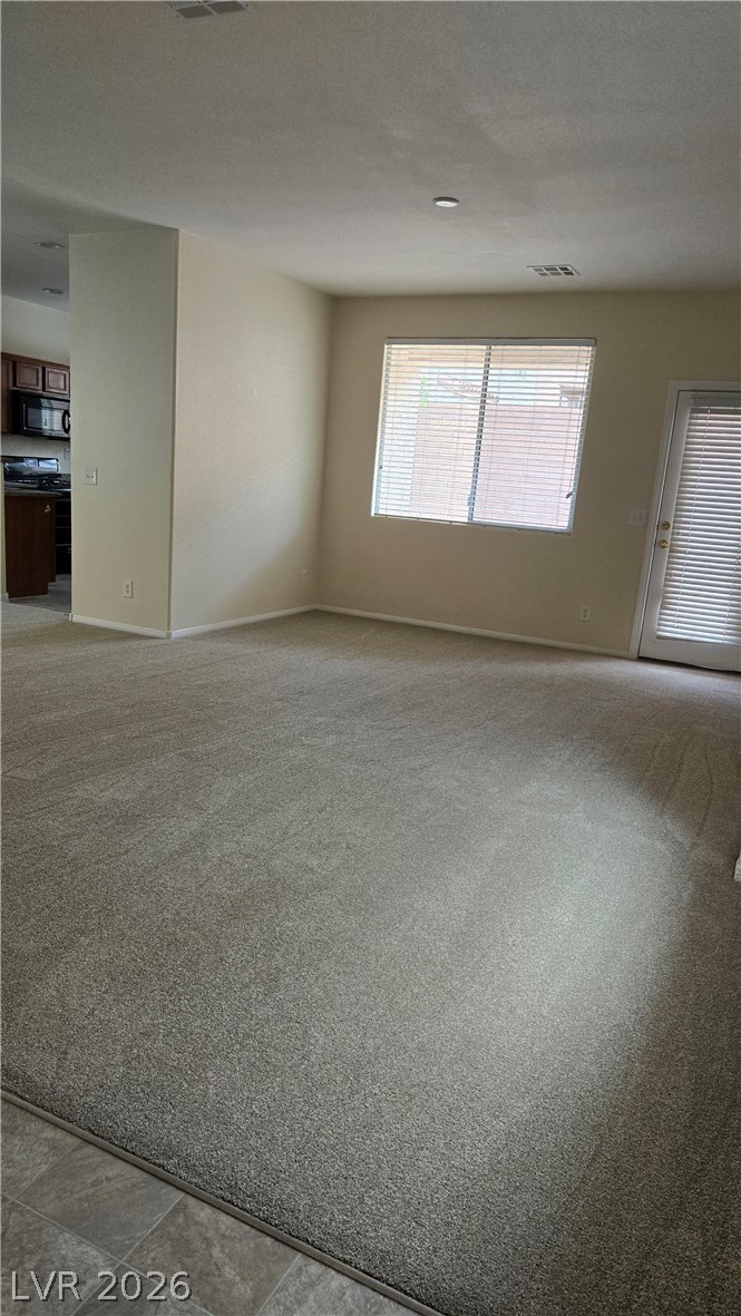 9031 Spring Star Court Las Vegas, NV 89148 - Photo 2 of 17 A spacious living area features fresh carpeting and natural light filtering through window blinds.
