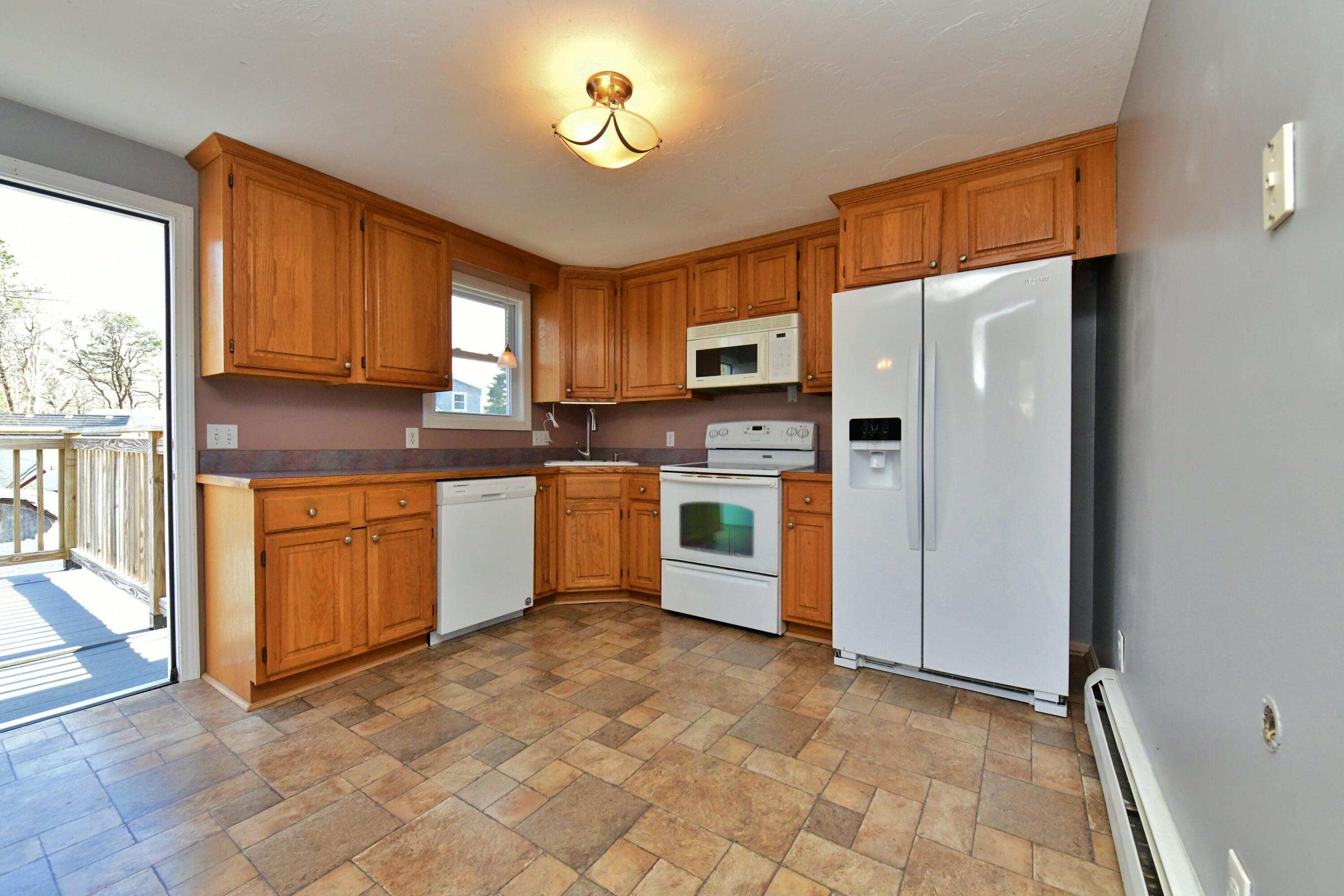 65 Siasconset Drive Sagamore Beach, MA 02562 - Photo 18 of 53 a kitchen with stainless steel appliances granite countertop a stove a refrigerator a sink a dining table and chairs with wooden floor