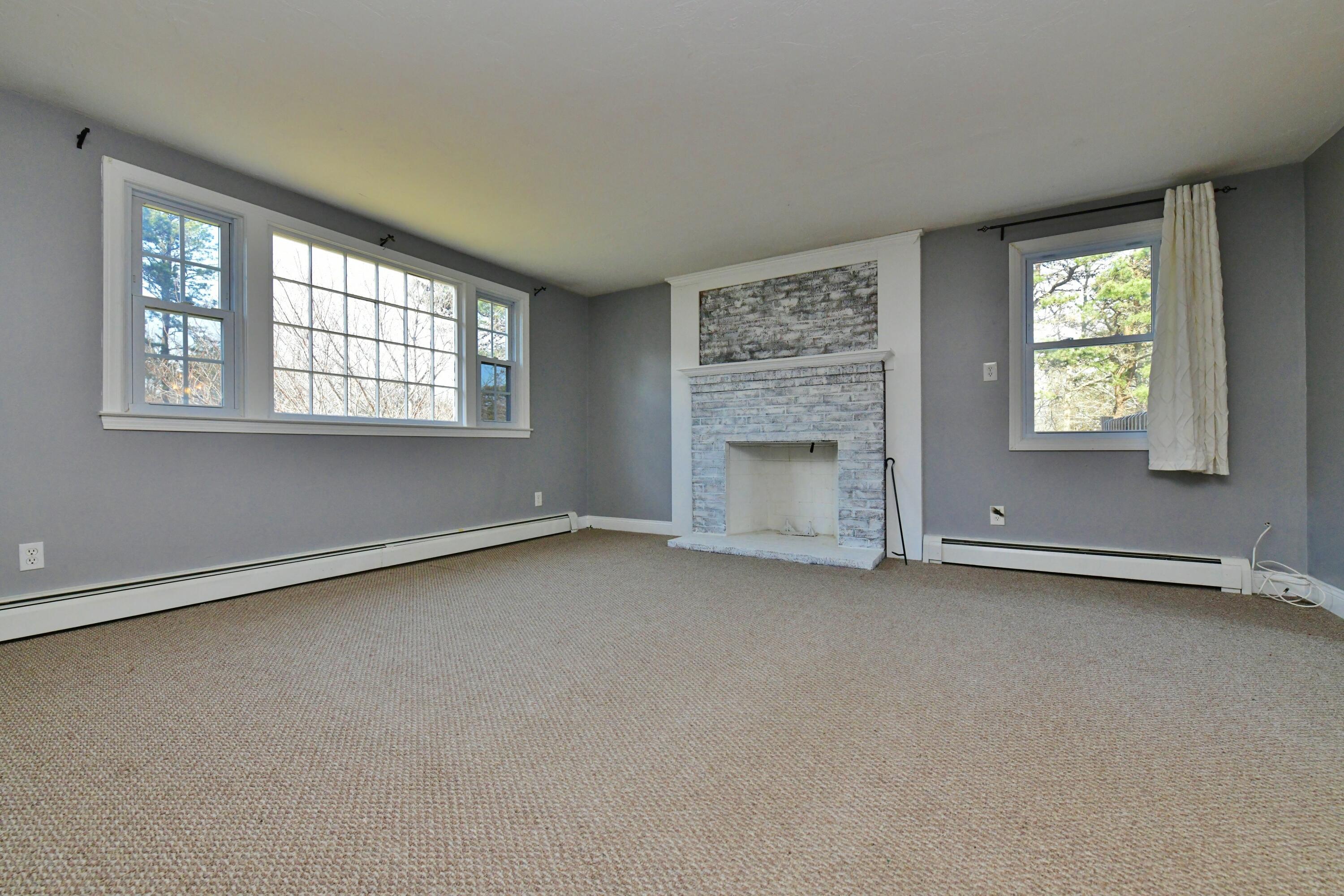 65 Siasconset Drive Sagamore Beach, MA 02562 - Photo 19 of 53 an empty room with a fireplace and windows
