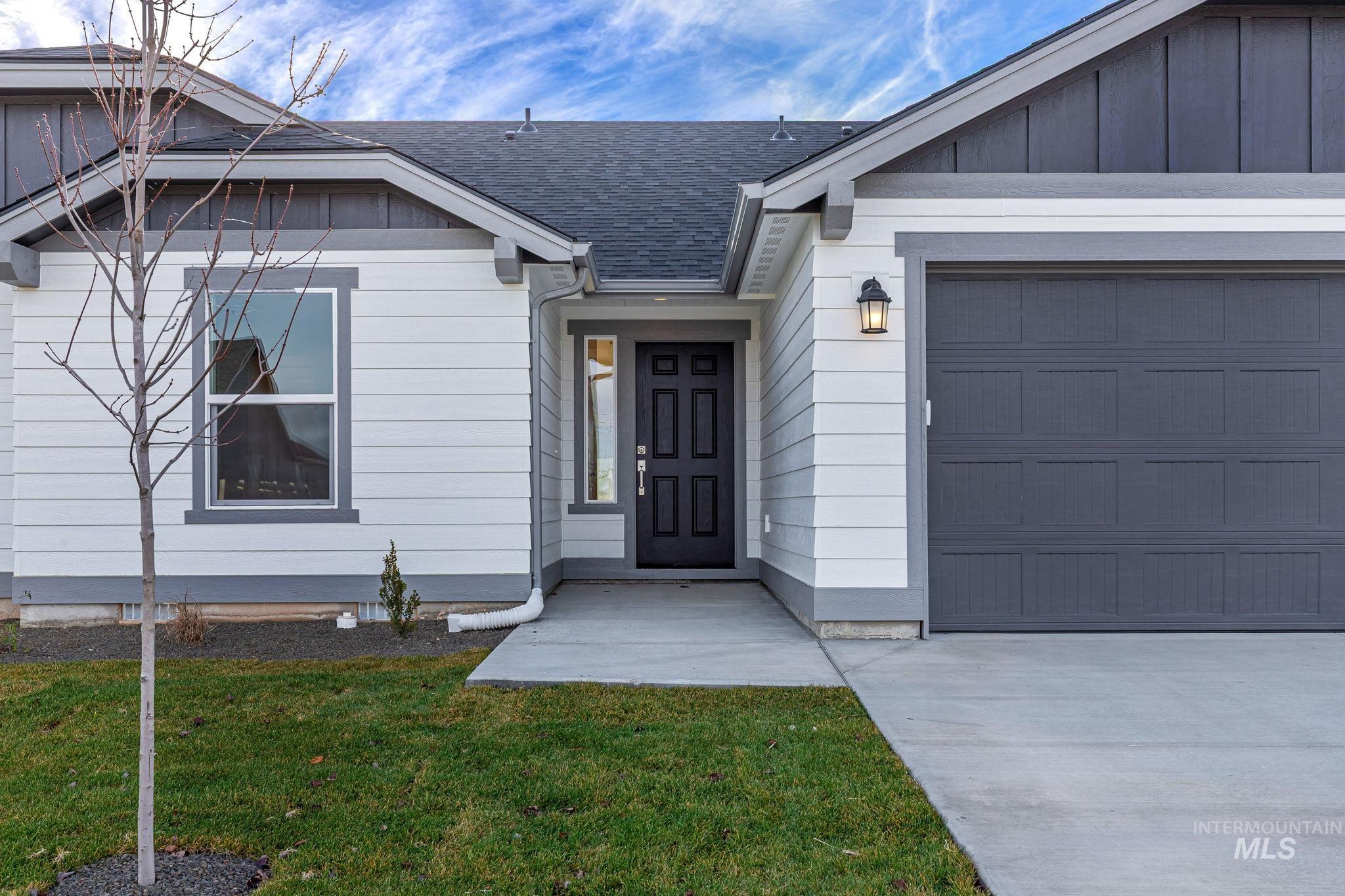 11363 Bluefield Drive Caldwell, ID 83605 - Photo 4 of 35 Entrance to property featuring an attached garage, a shingled roof, and a lawn