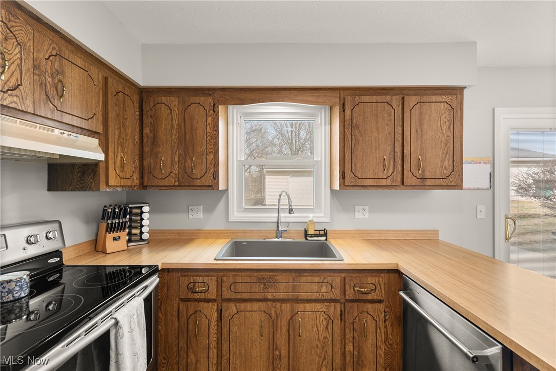 580 Orchardview Road Independence, OH 44131 - Photo 12 of 44 Kitchen with light countertops, appliances with stainless steel finishes, a sink, and under cabinet range hood
