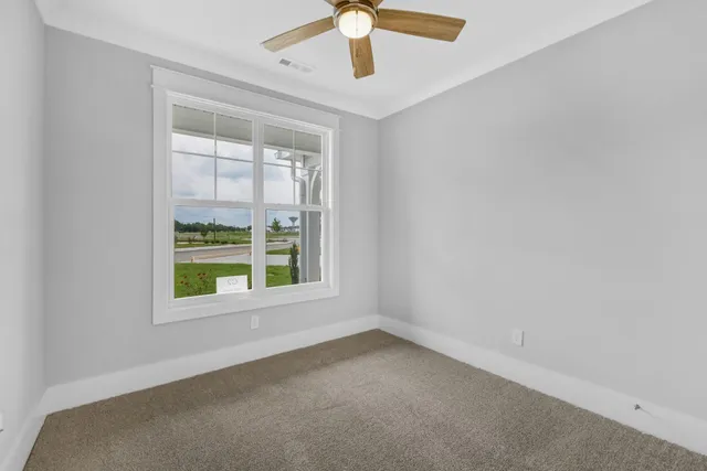 an empty room with windows and fan