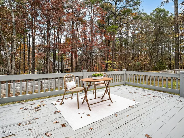 a view of a roof deck with chairs and wooden fence