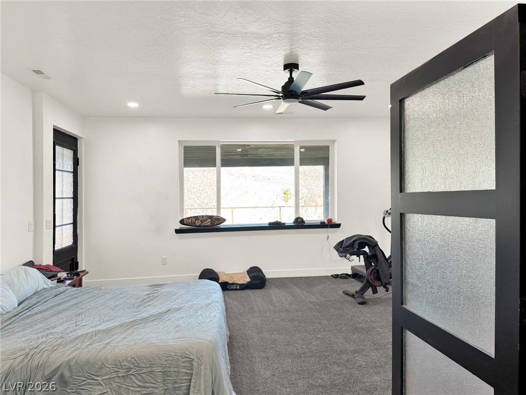 9393 North 93rd Highway Caliente, NV 89008 - Photo 18 of 41 A quiet bedroom retreat with a window overlooking the scenery and a dark ceiling fan providing air circulation.