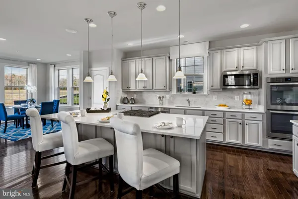 a kitchen with stainless steel appliances granite countertop a sink a stove a refrigerator cabinets a dining table and chairs