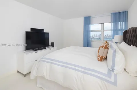 a bedroom with a bed and flat tv screen on the dresser