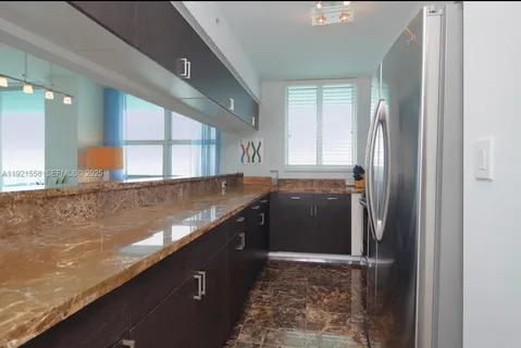 a kitchen with granite countertop a refrigerator and a sink