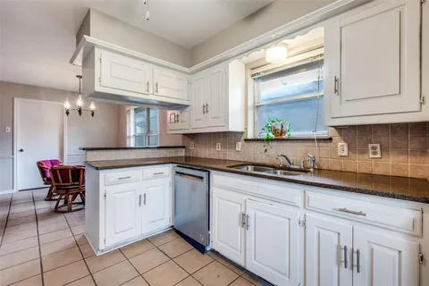 a kitchen with granite countertop white cabinets white appliances a sink and dishwasher