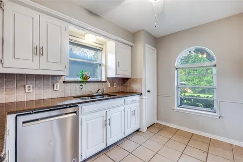 a kitchen with granite countertop white cabinets and window