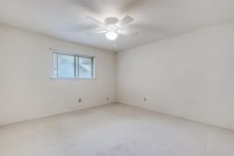 an empty room with chandelier fan and windows