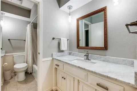 a bathroom with a granite countertop sink a toilet and a mirror