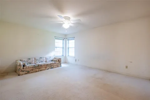 an empty room with chandelier fan and windows
