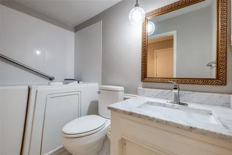 a bathroom with a granite countertop toilet sink and mirror