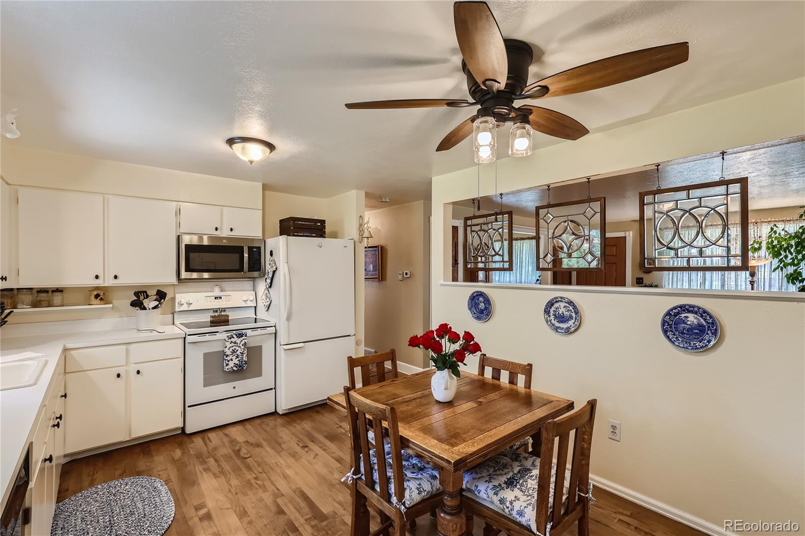 5366 Field Circle Arvada, CO 80002 - Photo 11 of 28 a kitchen with stainless steel appliances granite countertop a refrigerator a stove a sink dishwasher and a dining table with wooden floor