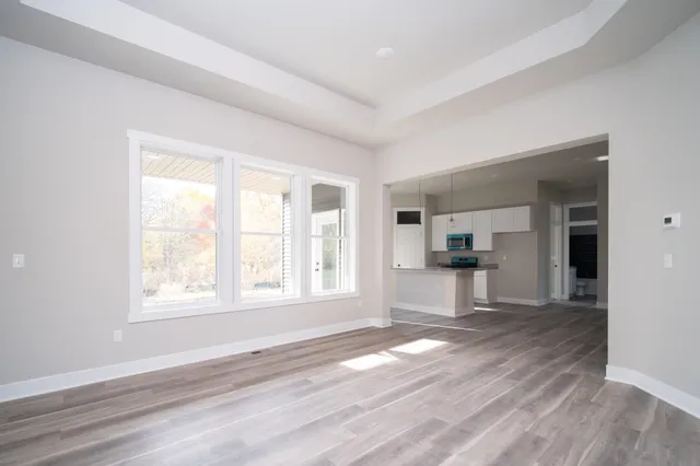 a view of empty room with wooden floor and kitchen view