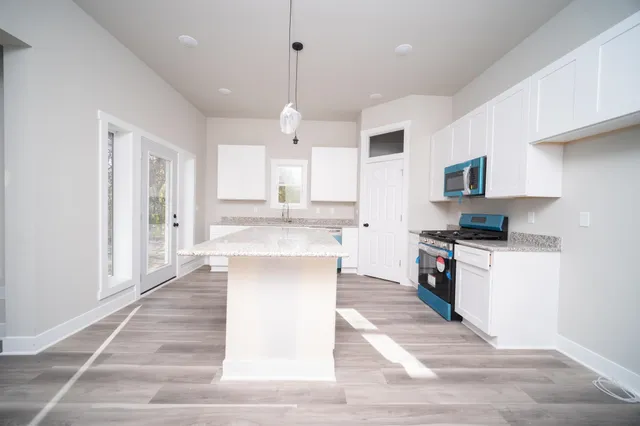 a large kitchen with granite countertop a stove top oven a sink dishwasher and a refrigerator with wooden floor