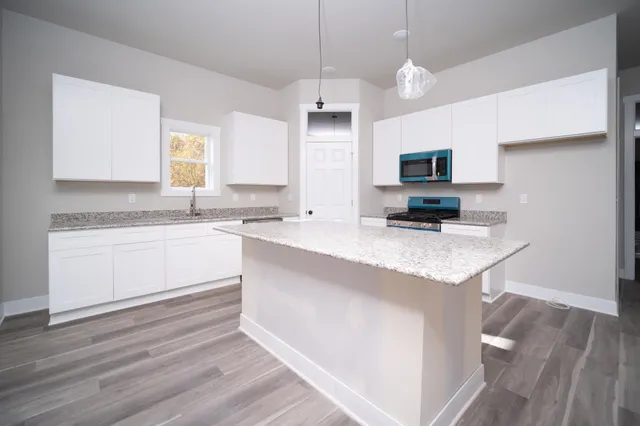 a kitchen with granite countertop a sink cabinets and wooden floor