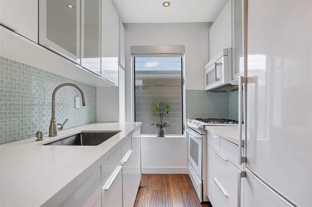 a kitchen with a refrigerator sink and white cabinets