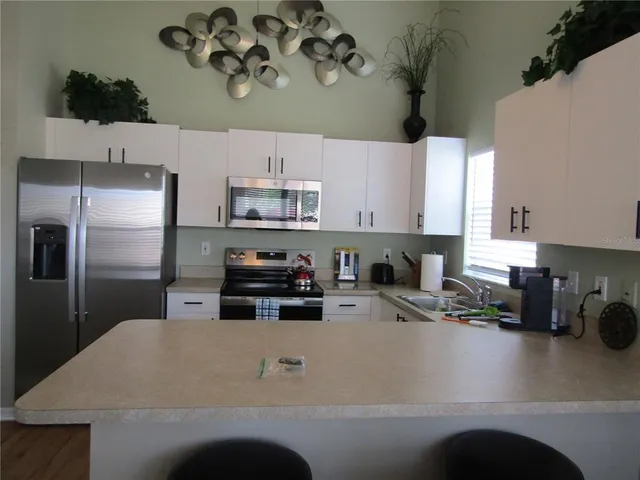a kitchen with kitchen island a white counter top space cabinets stainless steel appliances and cabinets