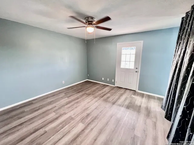 an empty room with wooden floor and a ceiling fan