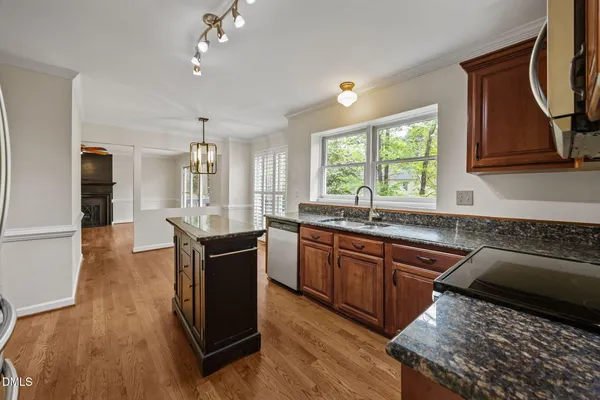 a kitchen with granite countertop a stove top oven a sink dishwasher and a refrigerator with wooden floor